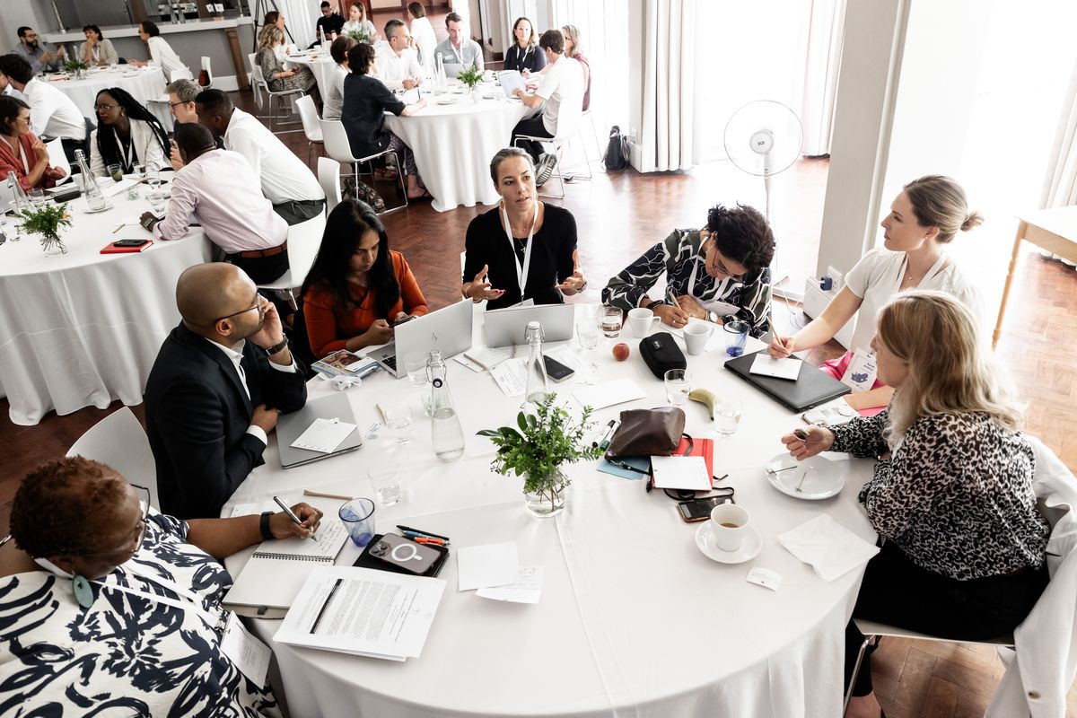 Beate van Loo-Born in discussion at a round table during a convening, delegates working around her.